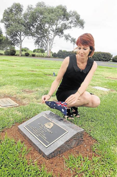 Western Districts Memorial Park co-owner Mel Henry places an Australian flag by the grave of an ex-serviceman.