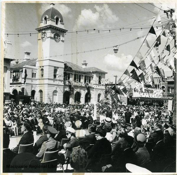 The main street was decorated with bunting when a crowd of people gathered for Dubbo's city declaration in 1966. Three men are perched on a window on the upper storey of the post office building. Image Macquarie Regional Library.