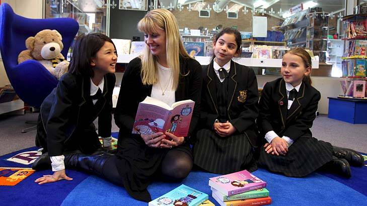 Novel approach to teaching … Jacqueline Harvey shows Jemma Tran, Shaniece Antoon and Ruth Alexander the latest book in the Alice-Miranda series.