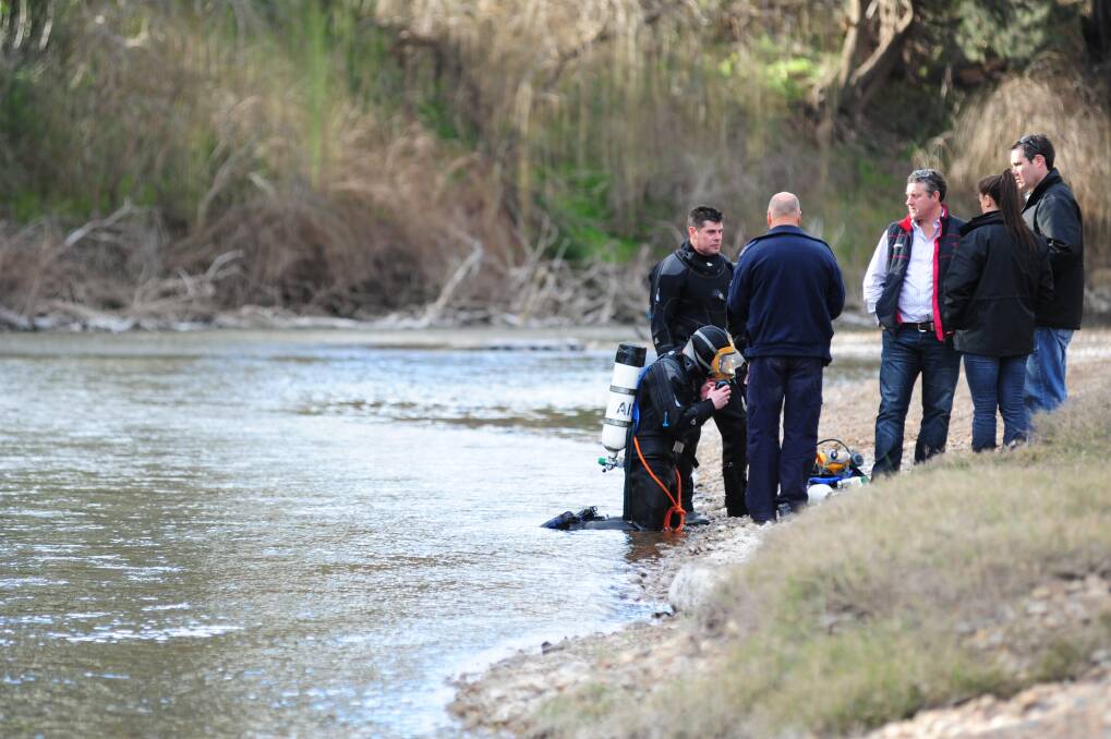 Orana Local Area Command detectives confer with Sydney-based police divers on teh banks of the Macquarie River below the Troy Bridge yesterday afternoon. Photo BELINDA SOOLE