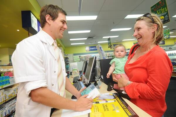 Pharmacist Tony Winmill has a laugh with Rebecca and Emma Austin.                Photo: AMY GRIFFITHS