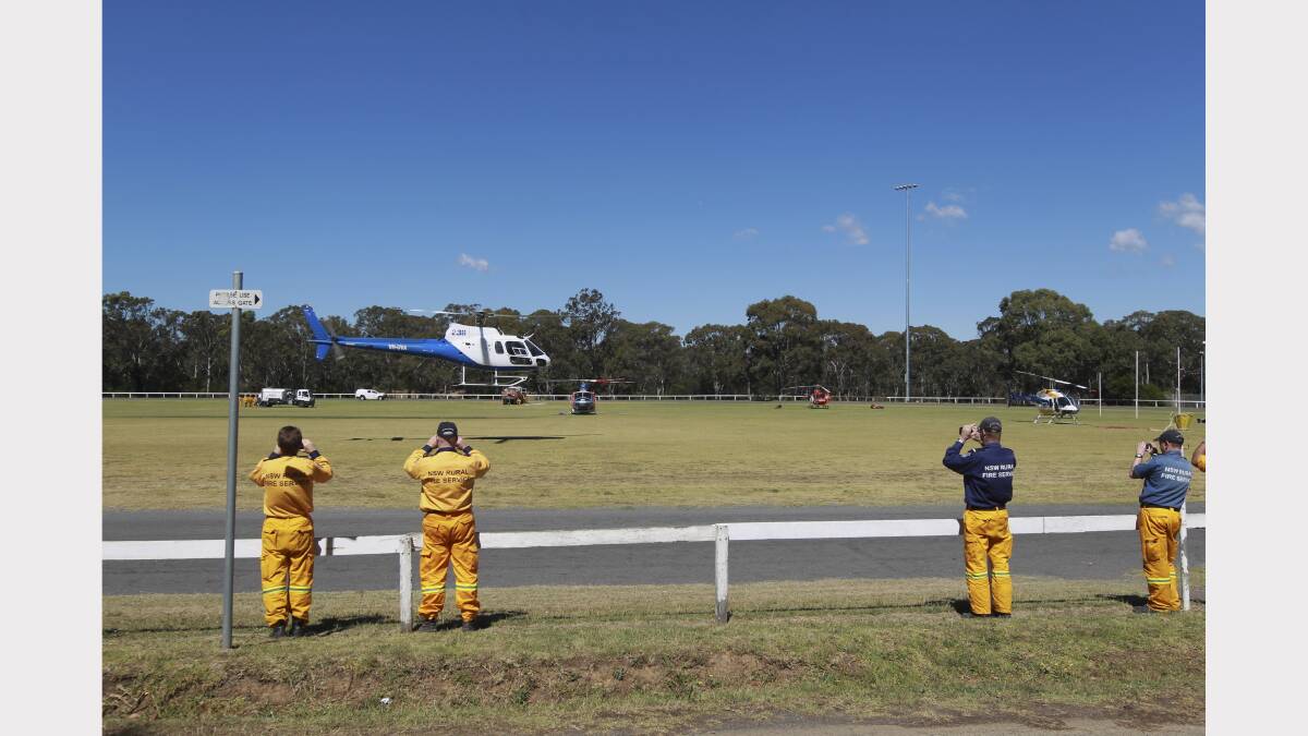  Firefighters at Bargo Oval in the Southern Highlands film a helicopter as it takes off on another water bombing mission today.