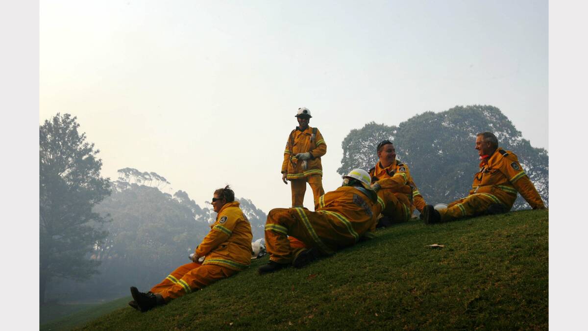   Image shows firefighters taking a break and watching a chopper firebomb at Dudley. Picture by  Darren Pateman