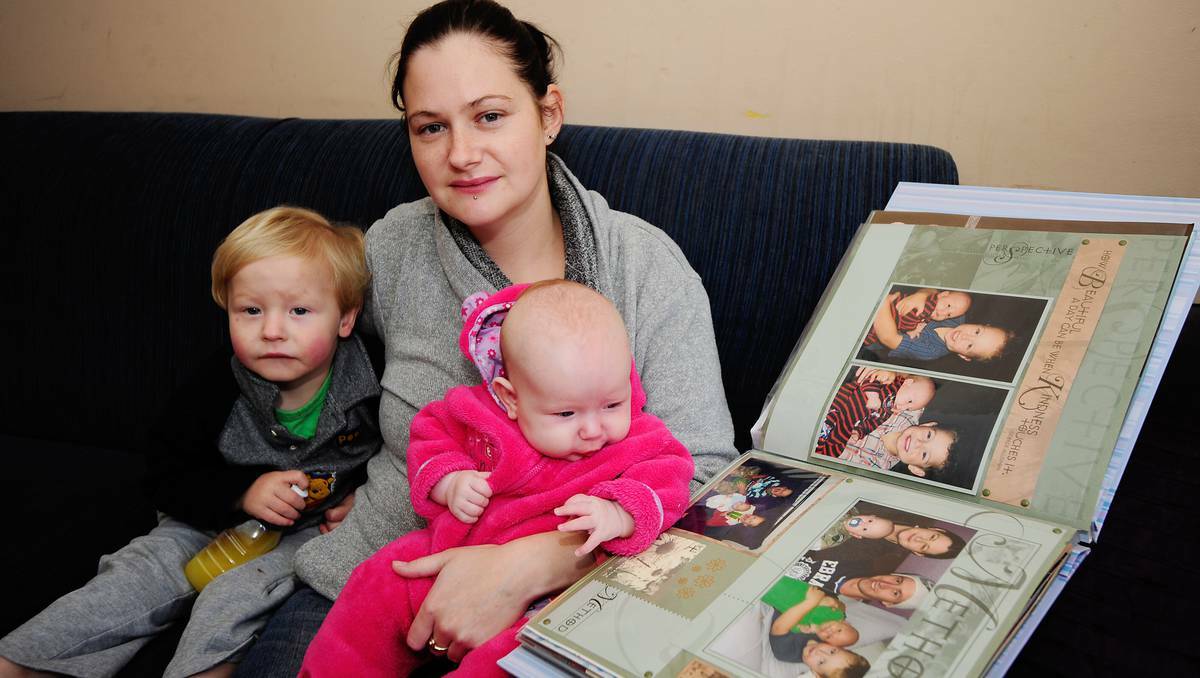 DUBBO: Wongarbon mother Sarah Williams cuddles son Ben, 2, and daughter Ruby, four months, as she shows them photographs of their deceased brother, Connor. A date has not been set for an inquest into the death of a little boy at Dubbo Base Hospital because witness statements are still being taken almost three years after the tragedy. . Photo: BELINDA SOOLE