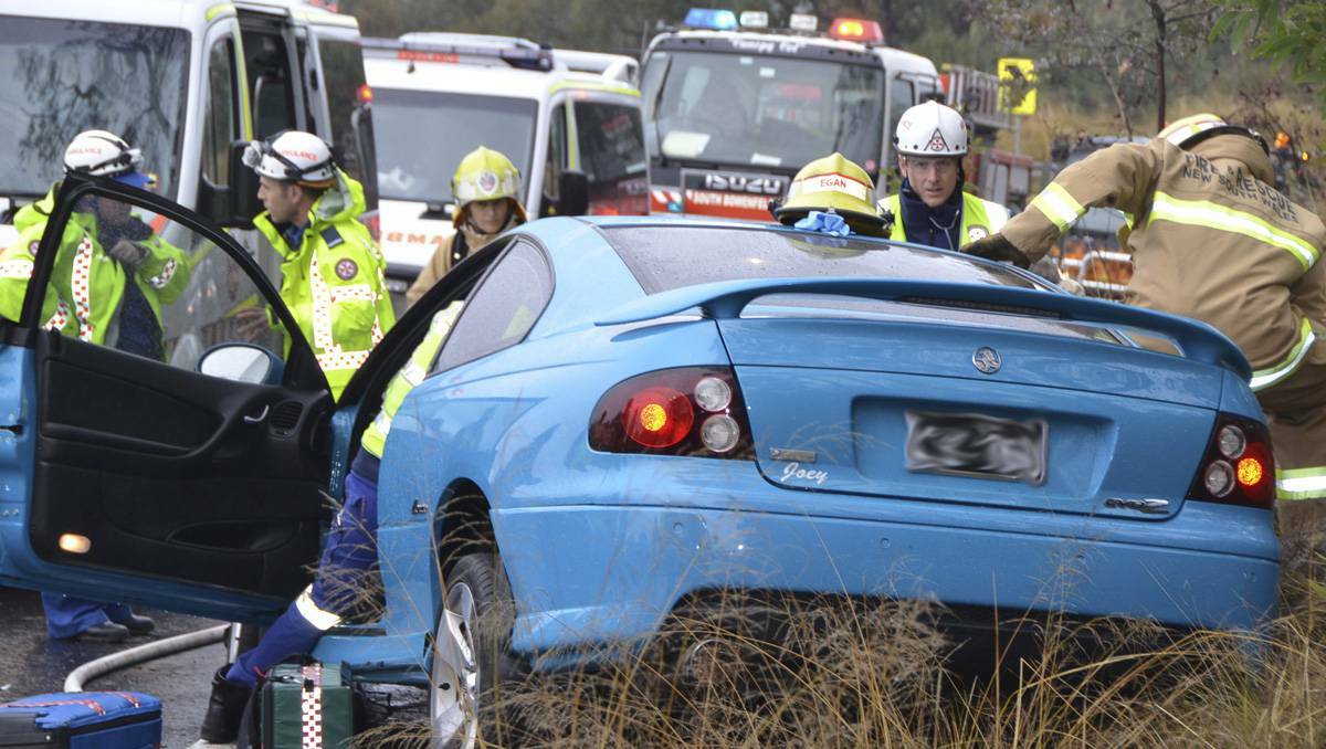 LITHGOW: Rescuers work to free a woman from her badly damaged car following the River Lett Hill crash. lm062413crash