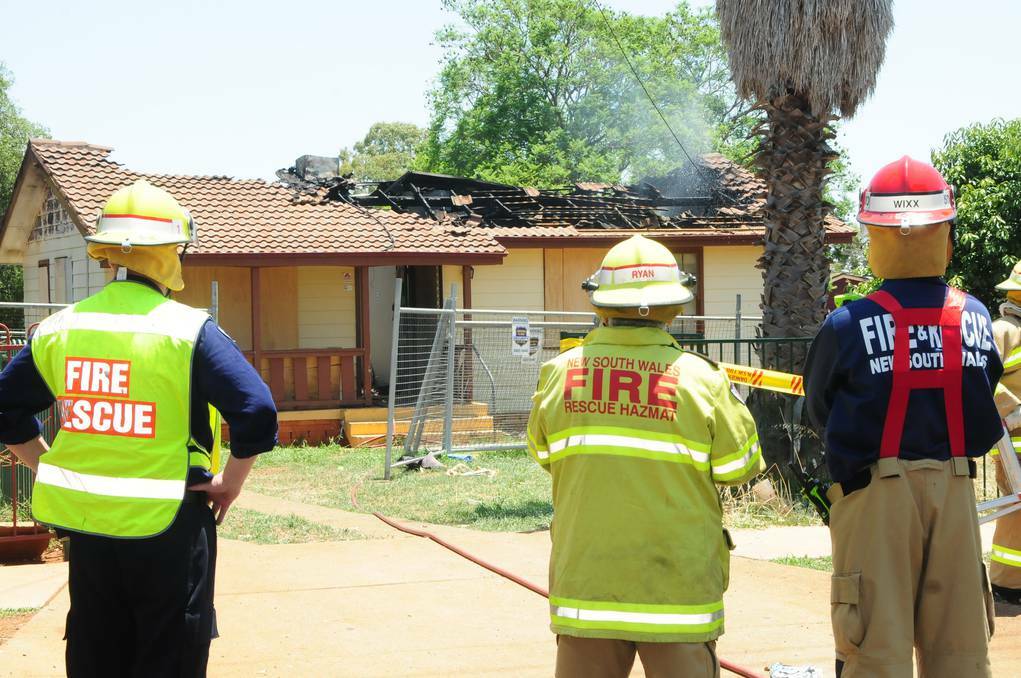 DUBBO: Members of Dubbo Fire and Rescue watch on as a small reignition of a fire in the roof of a Braun Avenue house is extinguished. The fire started in the boarded up house in the early hours of yesterday morning. Photo: KATHRYN O'SULLIVAN