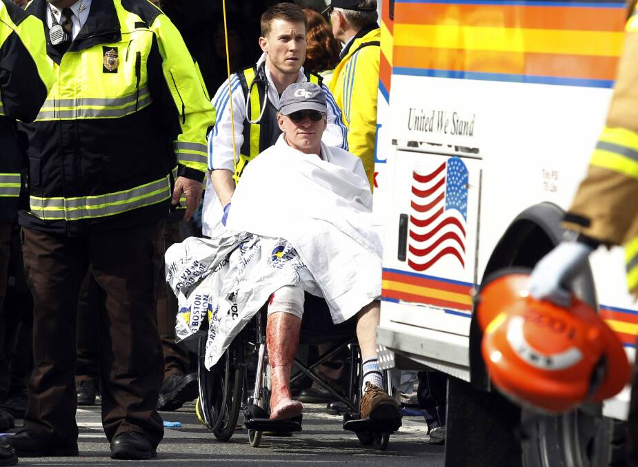 People comfort each other while emergency services attend the scene of the Boston blasts. Photo: Reuters