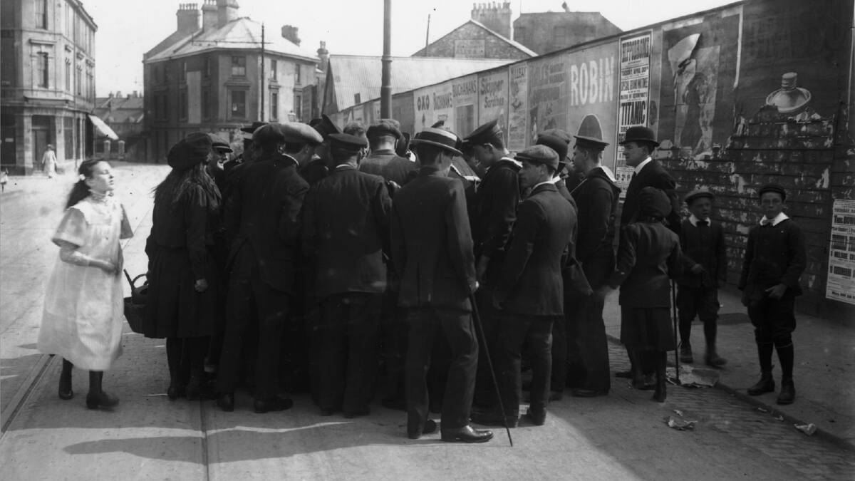 A crowd in Devonport, Devon gathers around a survivor of the Titanic disaster to listen to his account of the sinking. A poster on the wall behind them advertises a Titanic-related event at the local Hippodrome. Photo by Topical Press Agency/Getty Images
