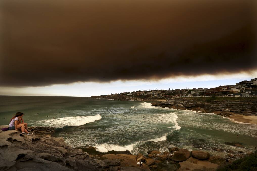 People watch from Tamarama headland as a wave of smoke haze caused by bushfires accross NSW smothers the Eastern suburbs of Sydney. Photo: Brianne Makin 