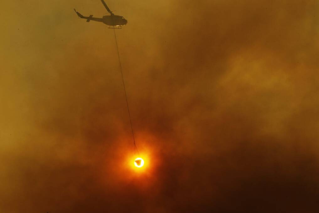 A water bombing helicopter at work in the Awabakal Reserve, Dudley / Redhead area. Photo: Max Mason Hubers