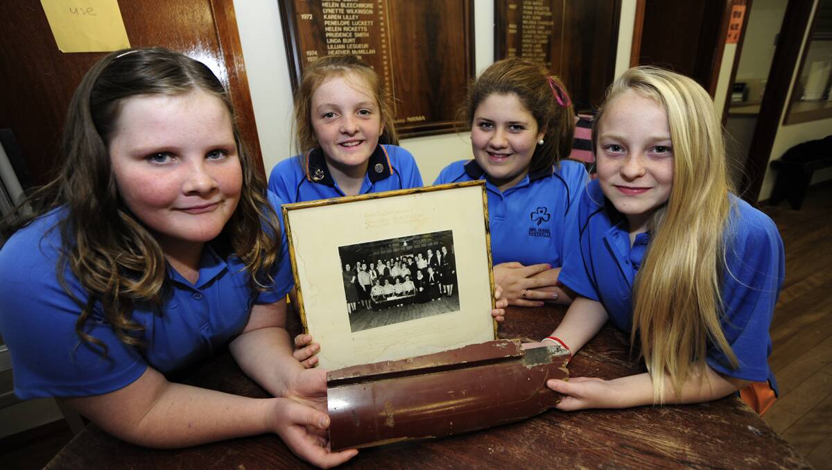 Current Girl Guides Hannah Tailby, Zoe Manton, Brooke Lewis and Katrina Reeves with mementoes from the 1963 Geurie rail crash. Guides and leaders involved in the disaster posed for a photograph and kept a piece of timber from their damaged rail carriage. The historic items have been on display at the South Dubbo Guide hall for 50 years. Photo: Belinda Soole