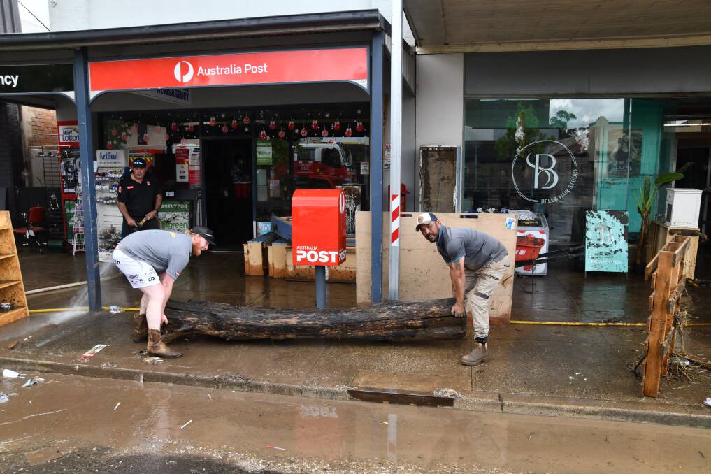 James Gavin and Johnny Pringle help move a tree that ended up in one of the shops on Bank Street, Molong. Picture by Carla Freedman
