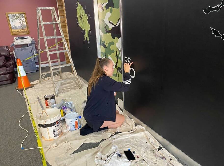 HARD AT WORK: 18 year-old artist Holly Faulds at work on a new mural for the Dubbo Escape Room. Now complete, the mural involves three doorways depicting the three challenges. Photo: DUBBO ESCAPE ROOM INSTAGRAM