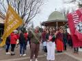 Two teachers holding banner flags for the NSW Teachers Federation (red) and Independent Education Union of Australia (yellow) at the protest march in Dubbo on 30 June 2022. Picture: Elizabeth Frias