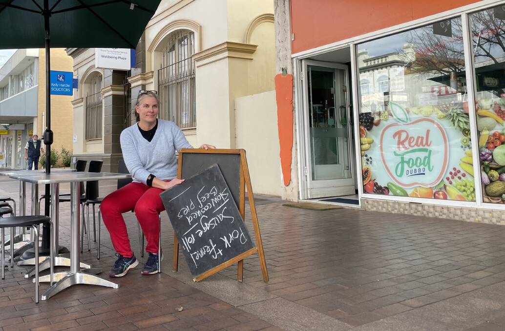 Real Food Cafe owner Sharon Campbell showing the recent board sign vandals have destroyed at her outdoor seating space on Macquarie Street. Picture: Elizabeth Frias