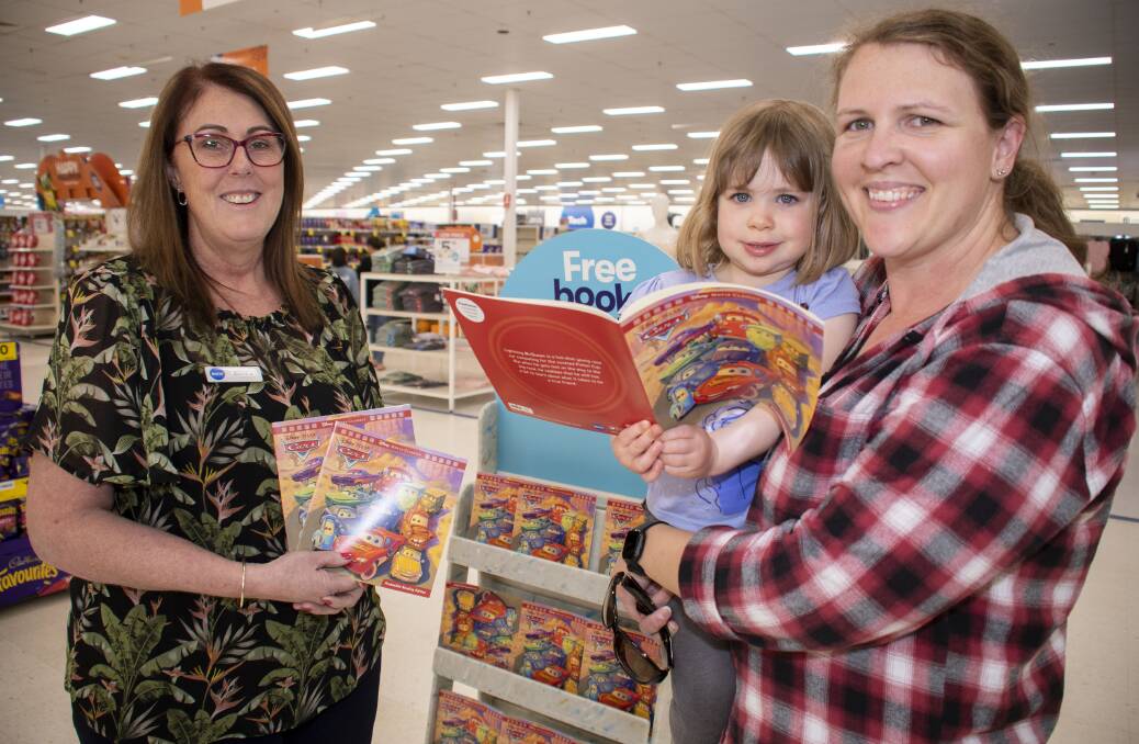 Big W Orana Mall store manager Sandra Dimmocks shows Norissa and her mother, Amanda Jarvis, the featured Walt Disney book, titled Cars, among the eight books free every Thursday at the store. Picture by Belinda Soole