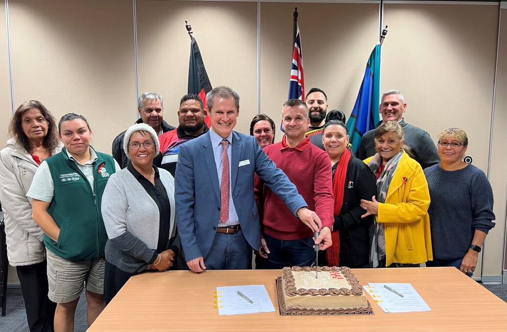 Mayor Mathew Dickerson and Dubbo Aboriginal Community Working Party chairperson Robert Riley, centre, cut a cake to celebrate the signing of a new partnership agreement. Picture: Supplied