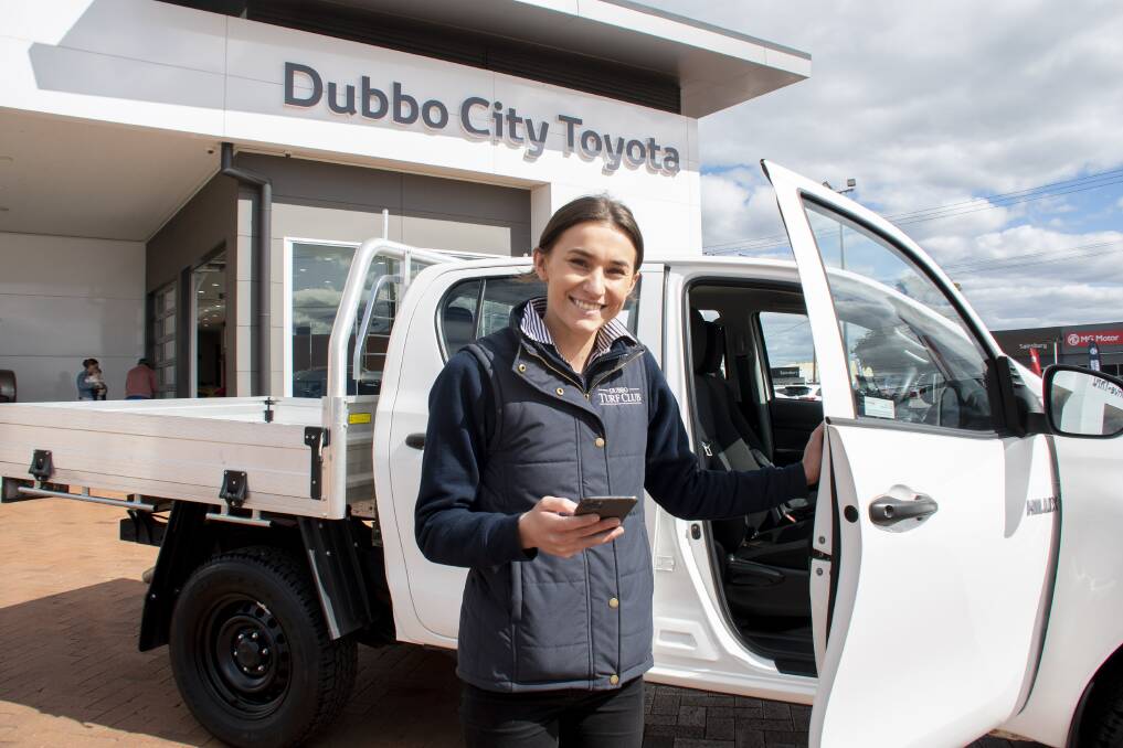 Claudia Morrison in front of Dubbo City Toyota, with a KINTO vehicle, holding open the app that allows her into the vehicle. Picture: Belinda Soole 