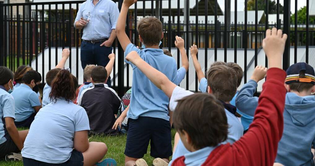 Students at Narromine Public School with their hands raised. Picture supplied 