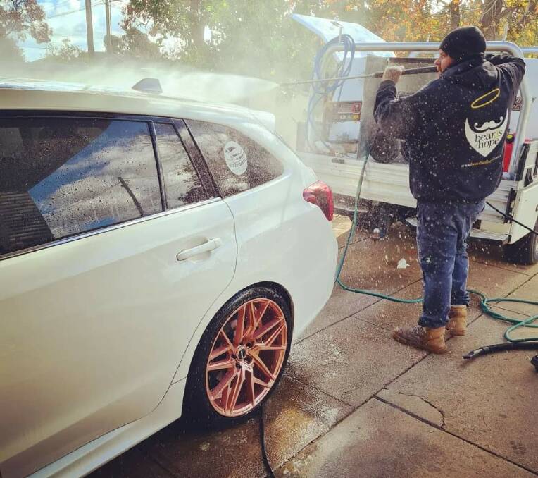 Jordan working on a car in his new Beards of Hope jumper. Picture: Supplied 
