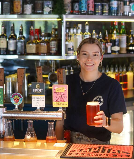 Kelsey Rowe behind the bar holding a beer. Picture supplied 