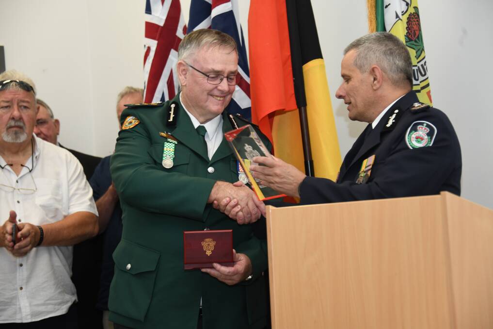 Mark Gibson receives a plaque for his dedication to the service from RFS commissioner Rob Rogers. Picture by Amy McIntyre 
