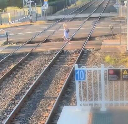 Foolish: A woman who strolled on the tracks at Woonons station, rushes across as she realises there's a freight train coming. Picture Transport for NSW