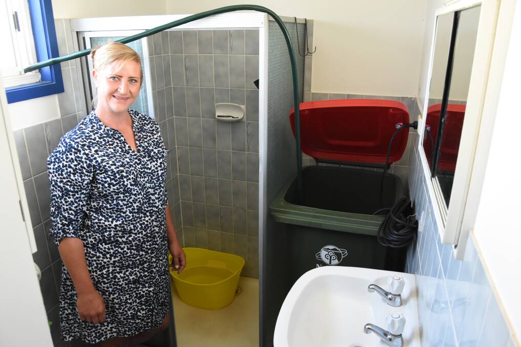 Creative solution: Crystal Osborne uses a baby bath to catch water before storing it in old Otto bin. The water is later pumped onto the lawn and garden. Photo: Mark Logan.