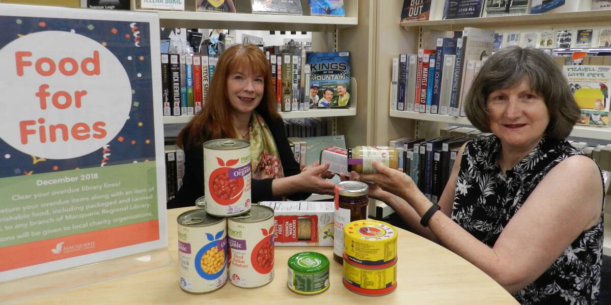 AMNESTY: Macquarie Regional Library's Kathryn McAlister and Heather Crosby with donations made as part of its  Food for Fines amnesty. Photo: Contributed