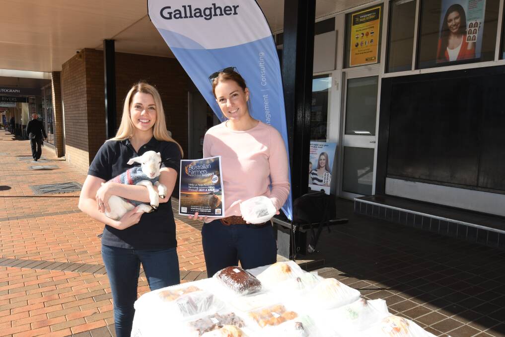 HELPING: Rebecca Allatt and Brooke Barber with a four-day-old lamb selling cakes and raffle tickets to raise money for farmers. Photo: BELINDA SOOLE