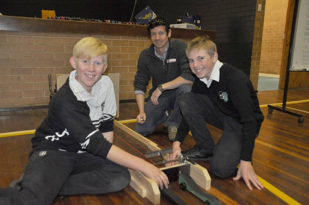 Delroy Year 8 students Douglas Willis and Logan Windsor, together with TAS head teacher James Peter, prepare cars to race