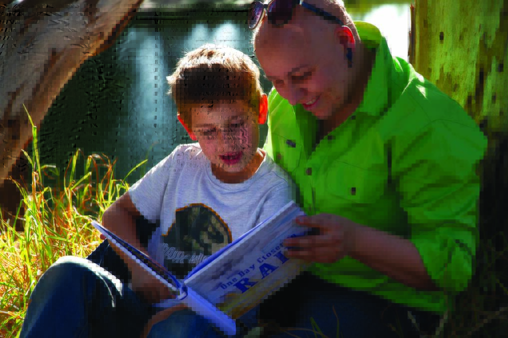 READING: Archie Valler and his mum Amy Naef reading on the banks of the Macquarie River in Dubbo. Photo: CONTRIBUTED