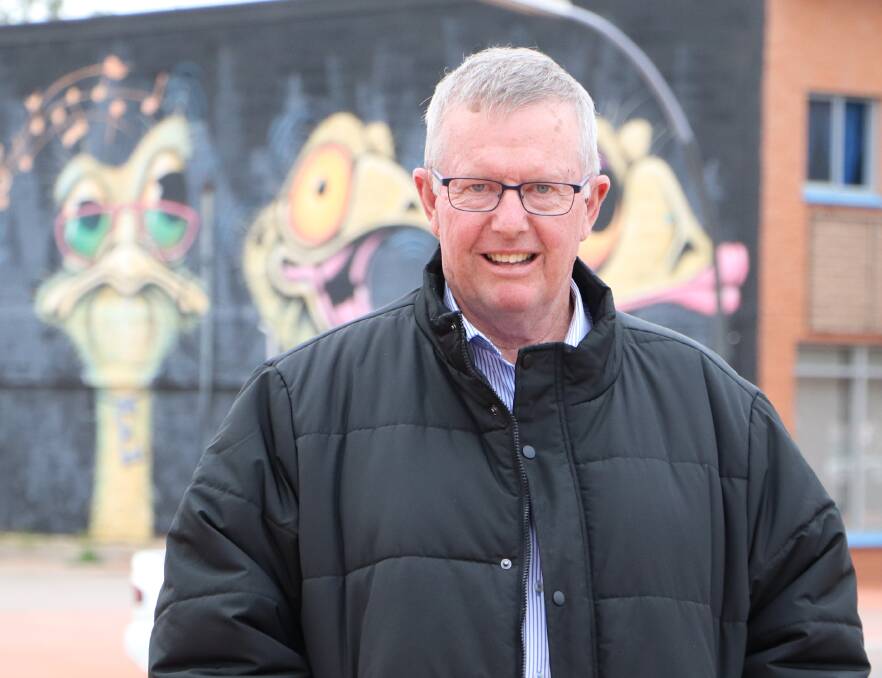Parkes MP Mark Coulton in front of a mural by previous Pave the Way to Gular festival artist John Murray from Lightning Ridge. Photo: CONTRIBUTED