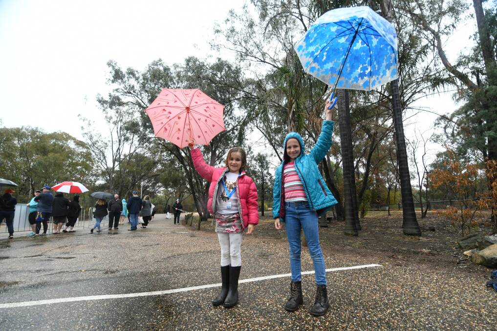 Let it Rain: Lara and Gemma Coote embrace the rain on Sunday. Photo: Amy McIntyre.