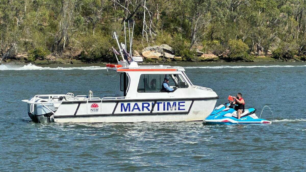 A NSW Maritime officer in a boat speaks with a person on a jet ski. Picture by NSW Maritime