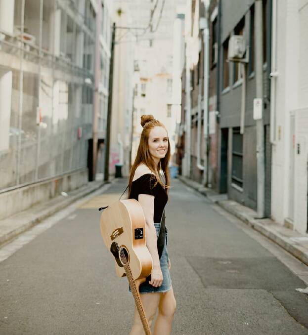 Singer-songwriter Grace Fuller stands in the street and has her guitar slung over her shoulder. Picture supplied