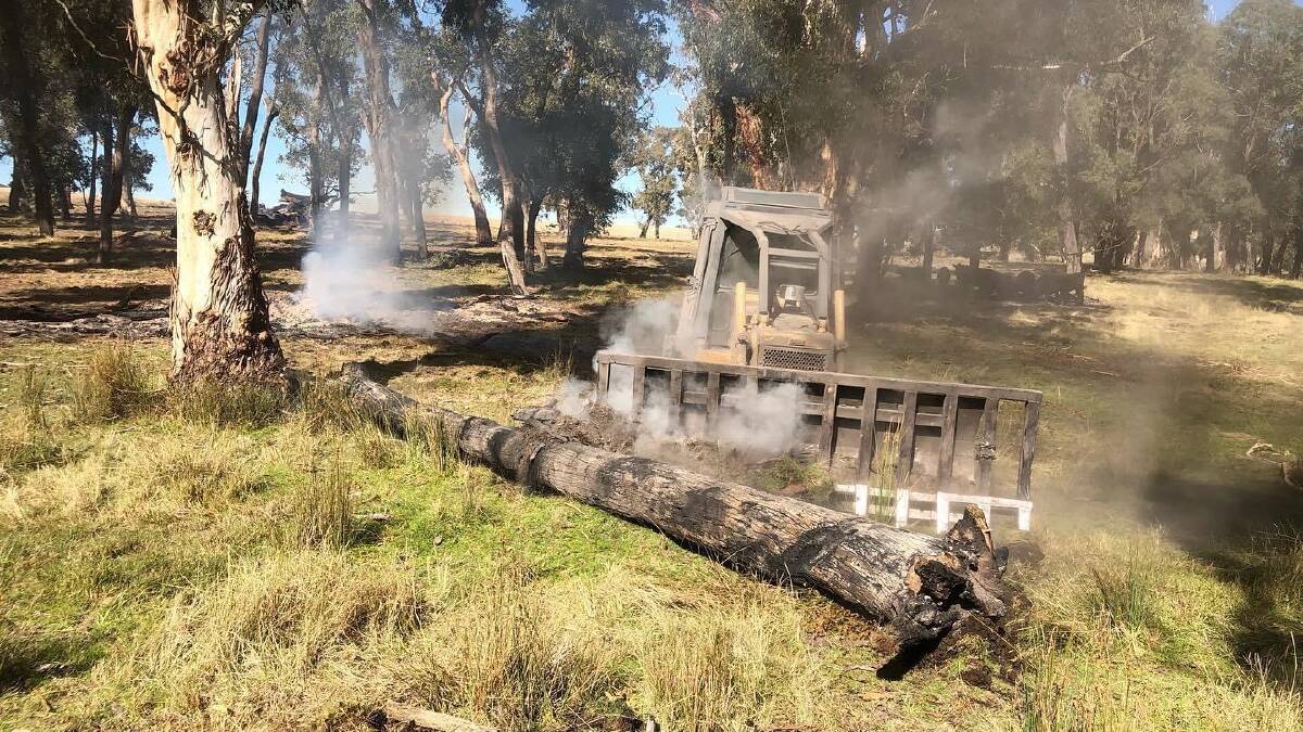 Sarah Laverty using machinery to put out a smouldering log. Picture supplied