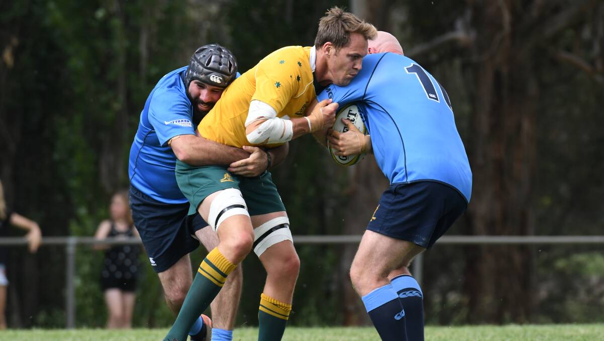 DOUBLE: Classic Wallabies general manager and No.8 Stephen Hoiles gets wrapped up by Central West Barbarians Tom Goolagong (left) and Dean Oxley (right). Photo: JUDE KEOGH