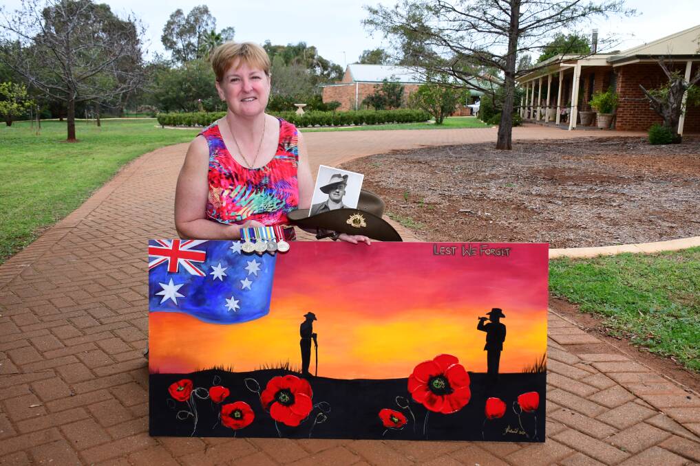 Lest We Forget: Dubbo's Sally Turner, holding a photo of her father and his war medals, at her driveway to pay her respects on Anzac Day. Photo: BELINDA SOOLE