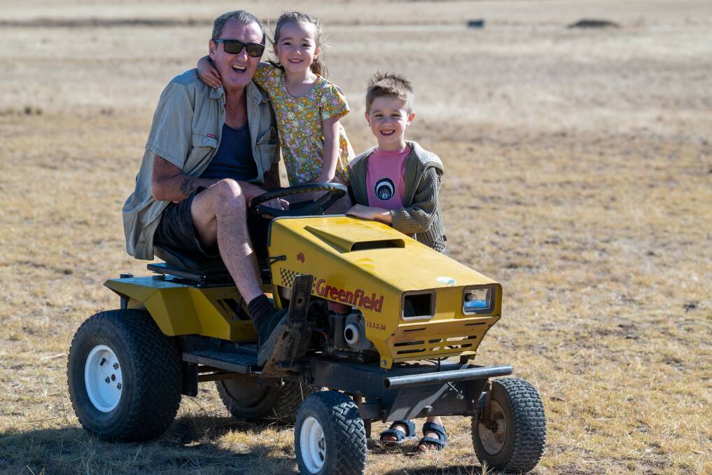 Warren Acott is about to ride this mower to Canberra in a push to get politicians to do more to fight motor neuron disease. Grandchildren Moby and Akiko have wished him luck. Picture by Enzo Tomasiello