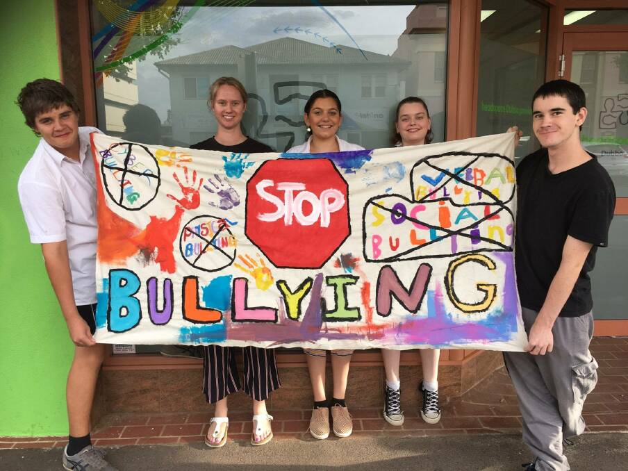 STOP IT: headspace Dubbo's Christina Rodgers (second from left) checks out a "stop bullying" banner made by its art group. Photo: Contributed