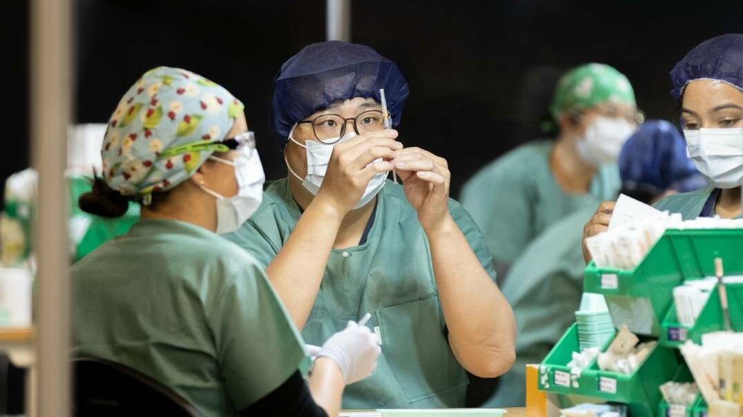  Staff prepare shots at government COVID vaccination clinic. Picture: Sitthixay Ditthavong 