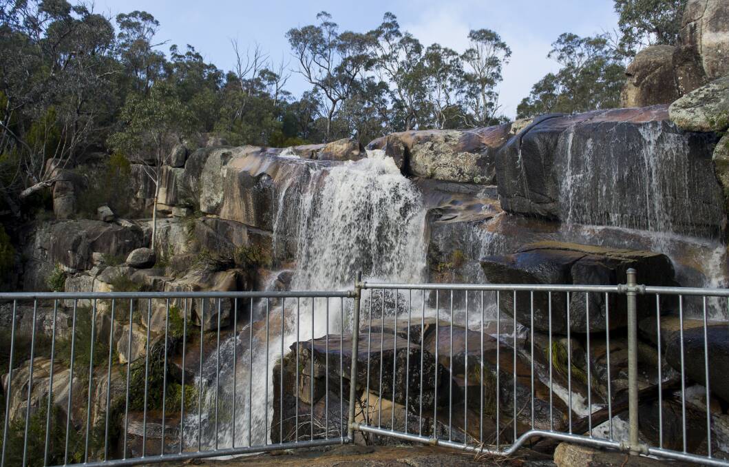 A safety raining is set up at the base of the falls for photographs but the ACT government does not consider the location a "swimming hole". Picture by Jay Cronan