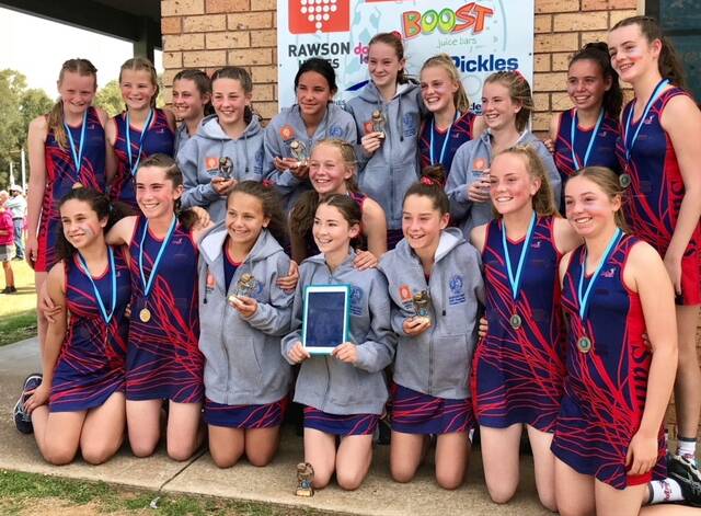 TOGETHER: The St Firebirds team gathers together after its grand final win with teammate Molly Croft on the iPad. Photo: CONTRIBUTED