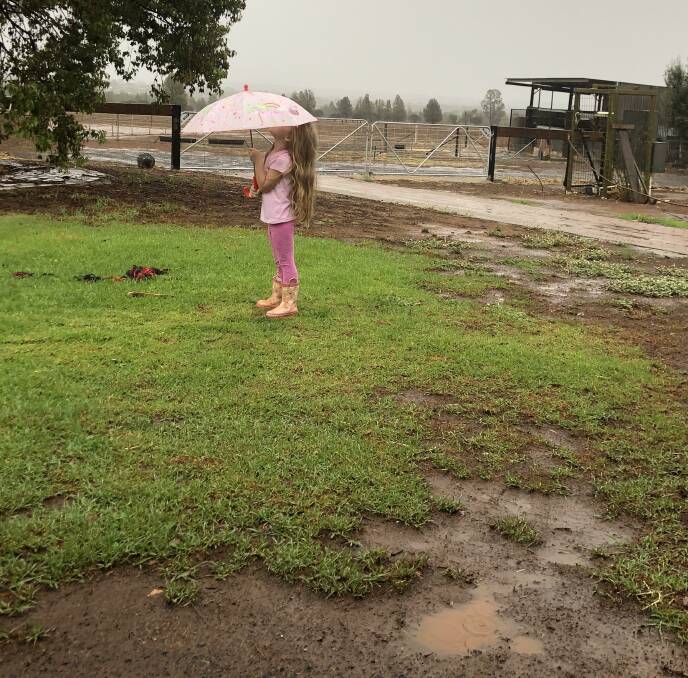 Gift from above: Mia Meek Houghton, 4, deploys her umbrella as rain falls, soaking the landscape. Photo contributed.