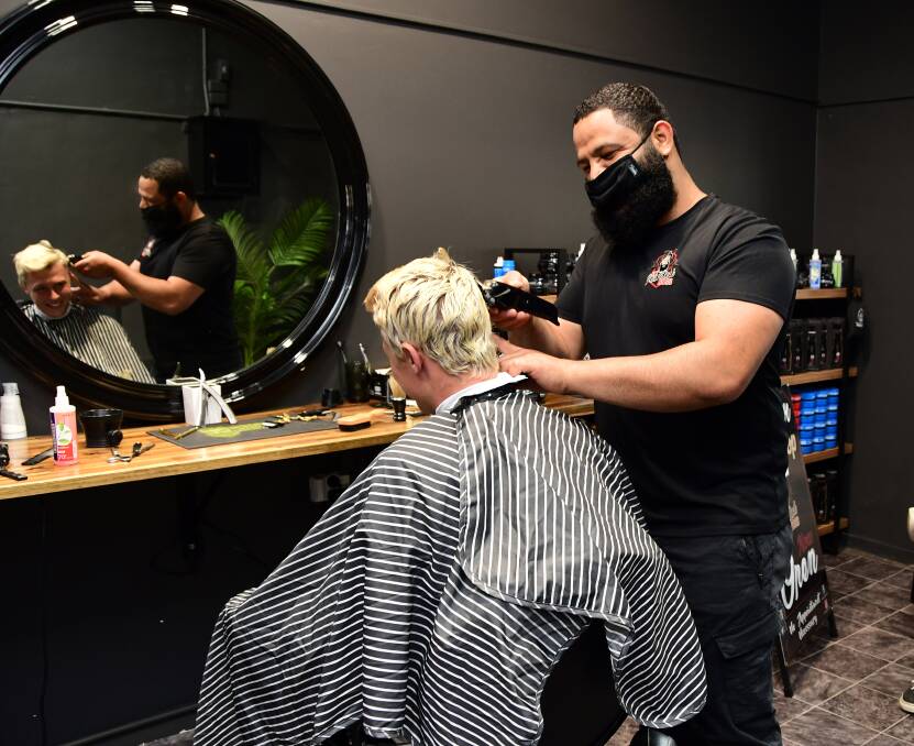 In demand: The Bearded Boss owner Walid Taleb gets the locks of one of his clients in order, one of 48 clients he saw on the first day of reopening. Photo: BELINDA SOOLE