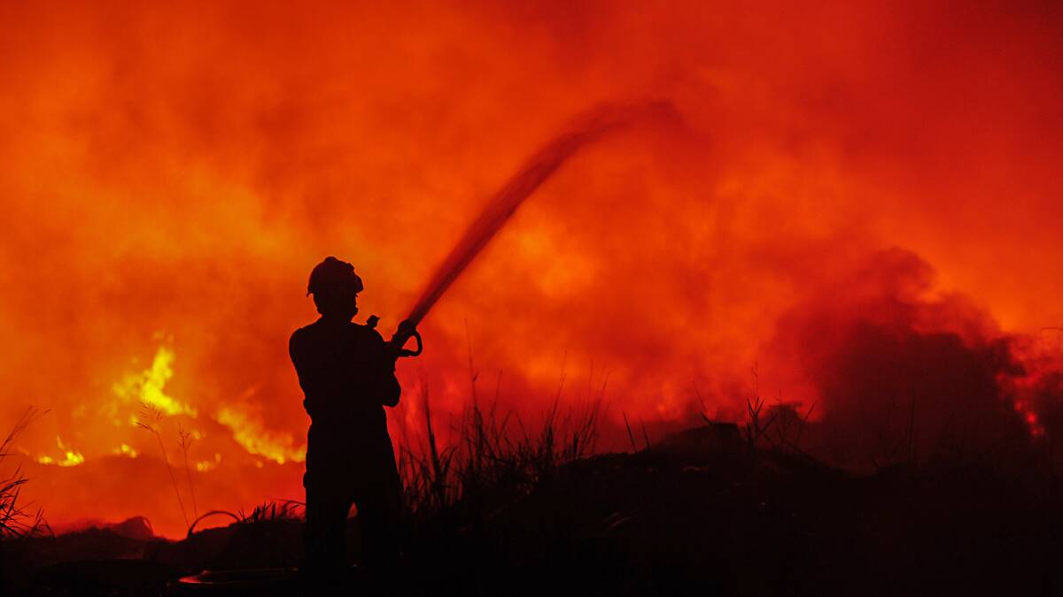 Firefighter hoses blaze. Photo: Shutterstock.