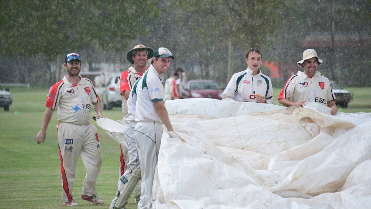 DOUSED: CYMS and Colts work together to get the covers on during the rain that cut short Saturday's match. PHOTO: AMY MCINTYRE.