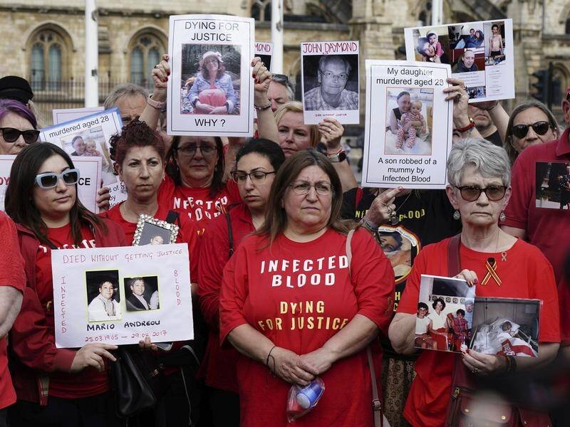 Infected blood campaigners gathered in Parliament Square before the report's release. (AP PHOTO)