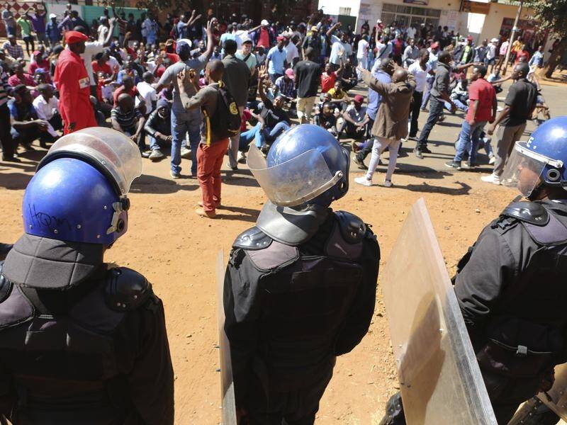 Police block opposition party supporters from entering the Zimbabwe Electoral Commission offices.